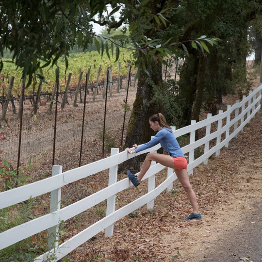 A female runner stretches on a fence