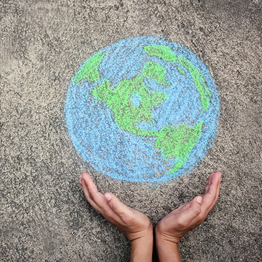 Hands holding up a chalk drawing of the Earth