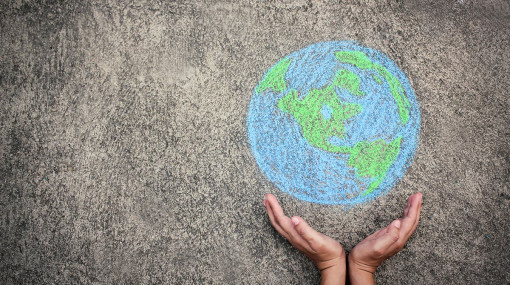 Hands holding up a chalk drawing of the Earth