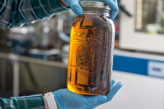 Photo of two hands in rubber gloves holding a mason jar full of cannabis oil