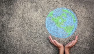 Hands holding up a chalk drawing of the Earth